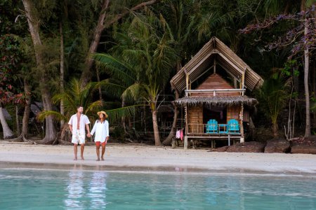 Téléchargez les photos : Un bungalow en bois de cabane de bambou sur la plage avec des palmiers. un jeune couple d'hommes et de femmes sur une île tropicale en Thaïlande en vacances, Koh Wai Island Trat Thaïlande - en image libre de droit