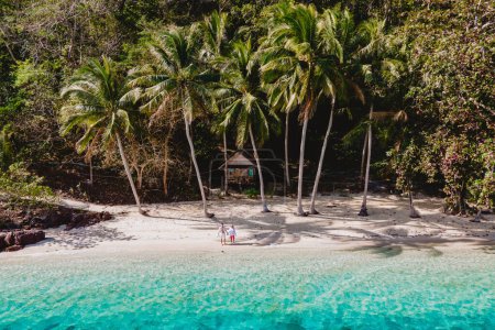 Téléchargez les photos : Koh Wai Island Trat Thaïlande près de Koh Chang. bungalow en bois de cabane de bambou sur la plage avec palmiers et océan bleu. un jeune couple d'hommes et de femmes sur une île tropicale en Thaïlande - en image libre de droit