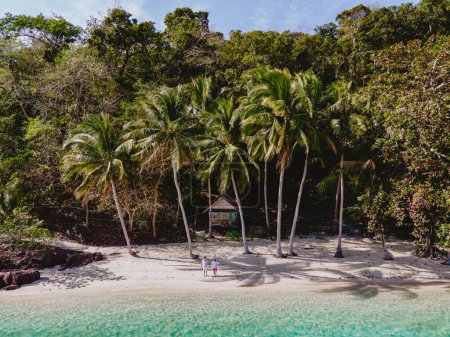Téléchargez les photos : Koh Wai Island Trat Thaïlande près de Koh Chang. bungalow en bois de cabane de bambou sur la plage avec palmiers et océan bleu. un jeune couple d'hommes et de femmes sur une île tropicale en Thaïlande - en image libre de droit