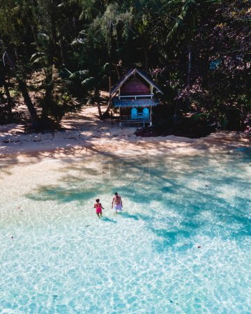Téléchargez les photos : Koh Wai Island Thailand est une île tropicale minuscule près de Koh Chang. bungalow en bois de cabane de bambou sur la plage. un jeune couple d'hommes et de femmes nageant dans l'océan bleu sur une île tropicale en Thaïlande - en image libre de droit