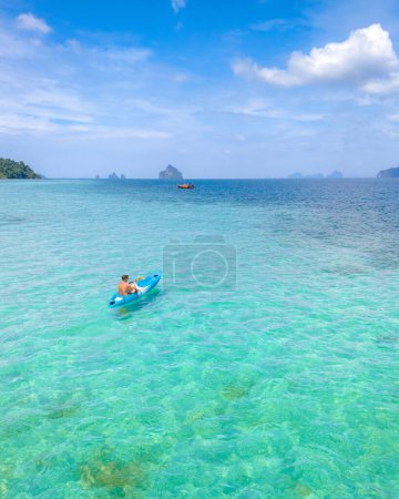 Photo for Young men in a kayak at the bleu turqouse colored ocean of Koh Kradan a tropical island with a coral reef in the ocean, Koh Kradan Trang Thailand on a sunny day with a blue sky - Royalty Free Image