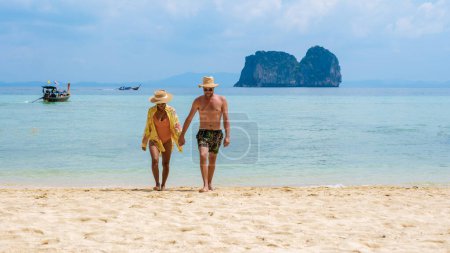 Photo for A couple of Thai women and European men on the beach of the tropical Island Koh Ngai island Thailand, with soft white sand, and a turqouse colored ocean in Koh Ngai Trang Thailand - Royalty Free Image