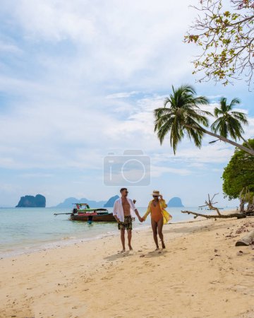 Téléchargez les photos : Heureux jeune couple, une femme asiatique et homme européen sur la plage de l'île de Koh Ngai, sable blanc doux, et un océan de couleur turque à Koh Ngai Trang Thaïlande - en image libre de droit