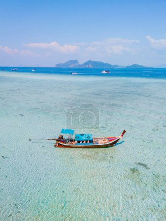 Téléchargez les photos : Bateau à queue longue dans l'océan bleu vert turqouse de couleur avec de l'eau claire à Koh Kradan une île tropicale à Trang Thaïlande - en image libre de droit