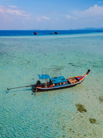 Foto de Barco de cola larga en el océano de color turquesa con agua clara en Koh Kradan una isla tropical en Trang Tailandia, arrecife de coral frente a una isla tropical - Imagen libre de derechos