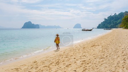 Photo for Woman walking at the beach at Koh Ngai island with palm trees and soft white sand, and a turqouse colored ocean in Koh Ngai Trang Thailand - Royalty Free Image