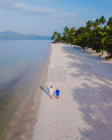 Foto de Vista del dron en una pareja caminando en la playa tropical de arena blanca de Koh Muk con palmeras de arena blanca suave, y un océano de color turquesa en Koh Mook Trang Tailandia en una tarde soleada - Imagen libre de derechos