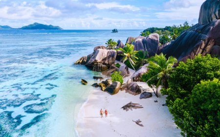 Photo for Anse Source d'Argent beach, La Digue Island, Seyshelles, Drone aerial view of La Digue Seychelles bird eye view.of tropical Island, couple men and woman walking at the beach during sunset at a luxury vacation - Royalty Free Image