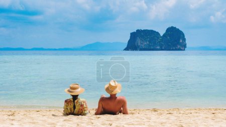 un par de hombres y mujeres sentados en la playa tropical de la isla de Koh Ngai, la parte trasera de una pareja acostada en la playa