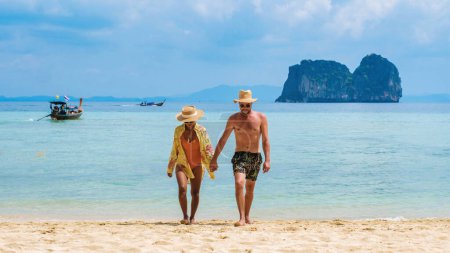 Téléchargez les photos : Un couple de femmes thaïlandaises et les hommes européens sur la plage de l'île tropicale Koh Ngai île Thaïlande, avec du sable blanc doux, et une turqouse couleur océan à Koh Ngai Trang Thaïlande - en image libre de droit