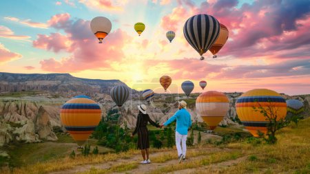 Photo for Kapadokya Cappadocia Turkey, a happy young couple during sunrise watching the hot air balloons of Kapadokya Cappadocia Turkey during vacation, a diverse couple of an Asian woman and caucasian man - Royalty Free Image