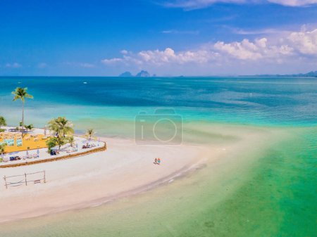 ein paar Männer und Frauen, die während eines tropischen Urlaubs in Thailand am Strand spazieren gehen, Koh Muk, eine tropische Insel mit Palmen, weichem weißen Sand und einem türkisfarbenen Meer in Thailand