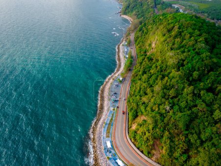 car driving on the curved road alongside the ocean beach road in summer. it's nice to drive on the beachside highway. Chantaburi Province Thailand, top drone view