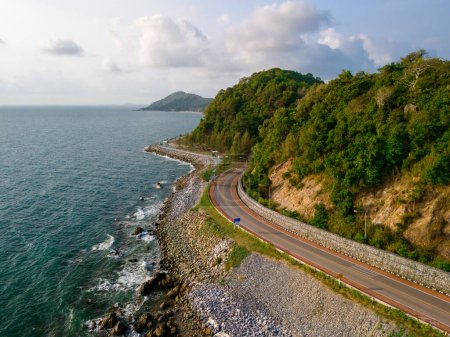 car driving on the curved road alongside the ocean beach road of Thailand. road landscape in summer. it's nice to drive on the beachside highway. Chantaburi Province Thailand, drone view