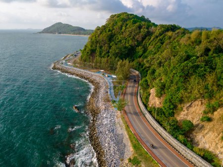 top view of a car driving on the curved road alongside the ocean beach road of Thailand. road landscape in summer. it's nice to drive on the beachside highway. Chantaburi Province Thailand, 