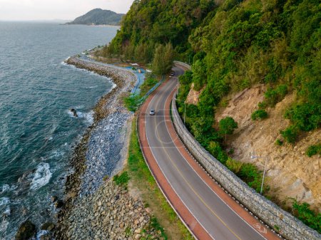 Photo for Car driving on the curved road alongside the ocean beach road of Thailand. road landscape in summer. it's nice to drive on the beachside highway. Chantaburi Province Thailand, at sunset, drone view - Royalty Free Image