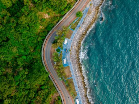 car driving on the curved road alongside the ocean beach road, top view at a road landscape in summer. it's nice to drive on the beachside highway. Chantaburi Province Thailand, 