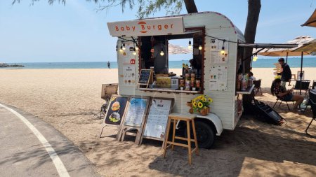 Foto de Rayong Tailandia 13 marzo 2024, Un vibrante camión de comida está estacionado en la orilla arenosa de una playa, sirviendo deliciosos platos a los asistentes a la playa bajo un cielo azul claro. - Imagen libre de derechos