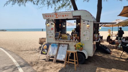 Foto de Rayong Tailandia 13 marzo 2024, Un vibrante camión de comida está estacionado en la playa de arena, sirviendo deliciosas comidas a los asistentes a la playa bajo el cielo soleado. - Imagen libre de derechos