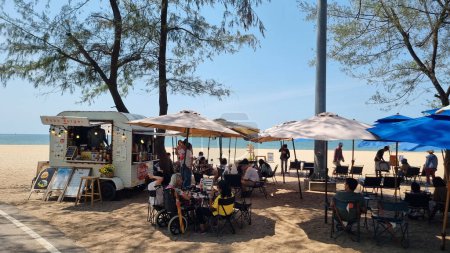 Téléchargez les photos : Rayong Thaïlande 13 mars 2024, Un groupe de personnes se détendant sous des parasols colorés sur une plage de sable, profitant du soleil chaud et des vues panoramiques sur l'océan. - en image libre de droit