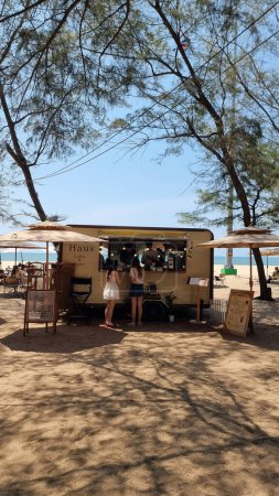Téléchargez les photos : Rayong Thaïlande 13 Mars 2024, Un camion de nourriture dynamique est stationné sur une plage de sable, offrant de délicieux repas aux amateurs de plage par une journée ensoleillée. - en image libre de droit