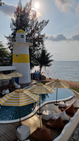 Photo for Bangsaray Pattaya Thailand 28 February 2024, Lounge chairs and umbrellas line the deck, offering a relaxing view of the lighthouse against the scenic backdrop. - Royalty Free Image
