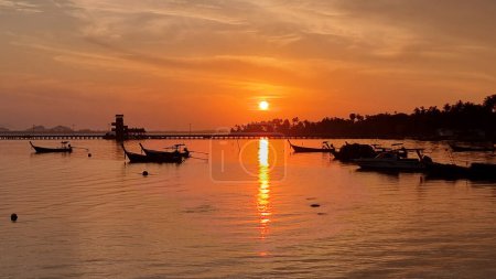 Photo for A picturesque scene of a group of longtail boats peacefully floating on the water under a sunrise sky. Koh Mook Thailand - Royalty Free Image