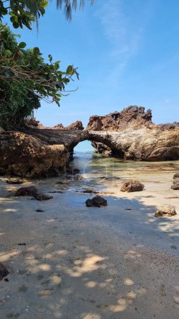 Foto de Una formación rocosa masiva domina la playa de arena, de pie sobre el telón de fondo de la serena costa. Koh Libong Tailandia - Imagen libre de derechos