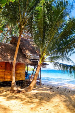 Eine traditionelle Hütte an einem Sandstrand, umgeben von hohen, schwankenden Palmen, die ein Gefühl von Ruhe und Frieden ausstrahlen. Koh Wai Thailand