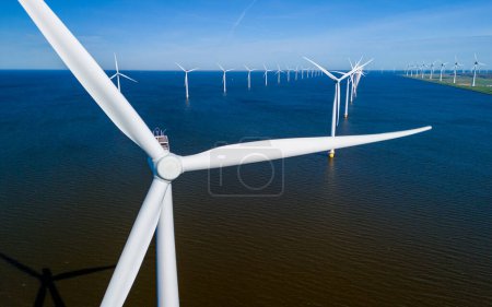 Photo for A vast body of water stretches out before the viewer, with numerous windmills standing tall in the background, set against a cloudy sky. windmill turbines in ocean - Royalty Free Image