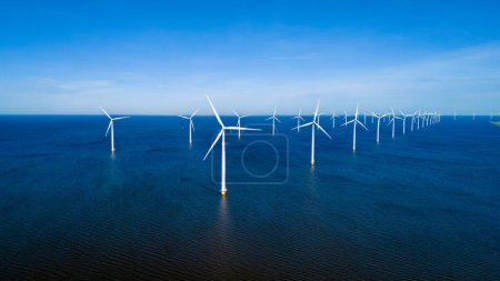 Foto de Un grupo de aerogeneradores se mantiene alto en el océano, aprovechando el poder del viento para generar energía limpia para los Países Bajos. - Imagen libre de derechos