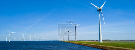 Une scène sereine aux Pays-Bas Flevoland, avec une rangée pittoresque d'éoliennes tournant gracieusement à côté d'un plan d'eau tranquille par une journée de printemps ensoleillée. éoliennes énergie verte