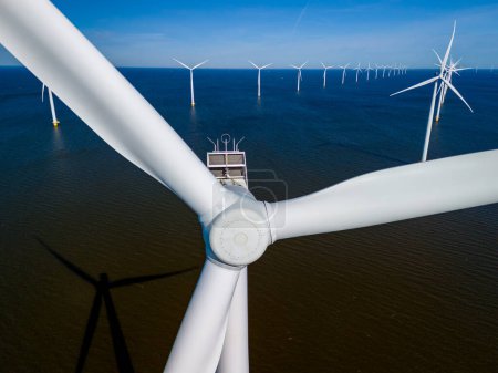Foto de Un parque eólico frente a la costa de los Países Bajos en Flevoland, aprovecha el poder de la brisa oceánica con turbinas imponentes en el horizonte. turbinas de molinos de viento energía verde en el océano - Imagen libre de derechos