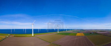 A mesmerizing aerial view capturing a wind farm near the ocean in the Netherlands Flevoland during the vibrant season of Spring.