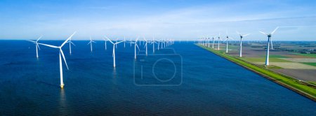 Téléchargez les photos : Une scène pittoresque de nombreux moulins à vent dispersés sur un vaste plan d'eau, face à une journée de printemps claire à Flevoland, Pays-Bas. éoliennes énergie verte dans l'océan - en image libre de droit