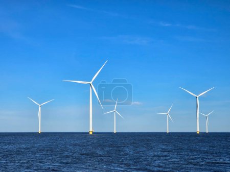 Photo for Windmill park in the ocean, view of windmill turbines generating green energy electrically, windmills isolated at sea in the Netherlands. - Royalty Free Image