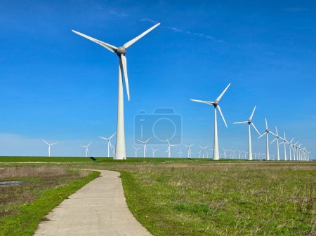 Photo for Windmill turbines on a Dutch dike generating green energy electrically windmills isolated at sea in the Netherlands. - Royalty Free Image