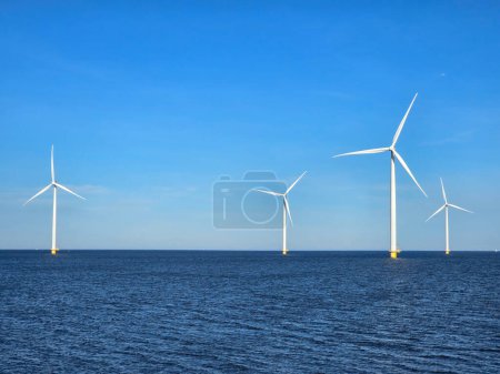 Photo for Windmill turbines in the ocean generate green energy electrically, and windmills isolated at sea in the Netherlands. Energy transition, zero emissions, carbon neutral, Earth day concept - Royalty Free Image