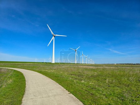 Foto de Vista de turbinas de molinos de viento en un dique holandés que genera energía verde eléctricamente, molinos de viento aislados en el mar en los Países Bajos. - Imagen libre de derechos