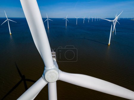 Eine Gruppe majestätischer Windkraftanlagen ragt hoch in den Ozean und nutzt die Kraft des Windes, um in Flevoland, Niederlande, während der dynamischen Frühlingszeit saubere Energie zu erzeugen..