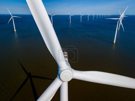 Foto de Un grupo dinámico de turbinas eólicas se mantiene alto en el océano, aprovechando la potencia del viento para generar energía renovable. turbinas de molinos de viento energía verde en el océano, transición energética - Imagen libre de derechos