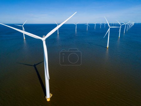 Eine Gruppe von Windrädern dreht sich majestätisch im Ozean und nutzt die Kraft des Windes, um saubere und nachhaltige Energie zu erzeugen. Drohnen-Luftaufnahme von Windkraftanlagen grüne Energie im Meer