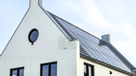 Téléchargez les photos : Panneaux solaires noirs sur le toit contre un ciel ensoleillé Gros plan d'une maison moderne avec des panneaux solaires noirs. Zonnepanelen, Zonne energie, Traduction : Panneau solaire, Énergie solaire - en image libre de droit