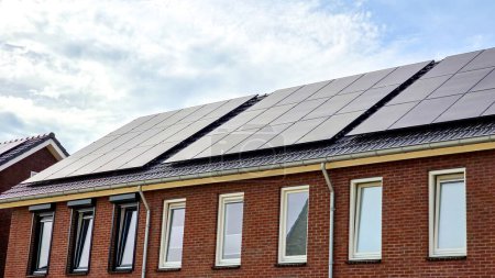 Photo for Modern houses with black solar panels on the roof against a sunny sky Close-up of new building with black solar panels. Zonnepanelen, Zonne energie, Translation: Solar panel, Sun Energy - Royalty Free Image