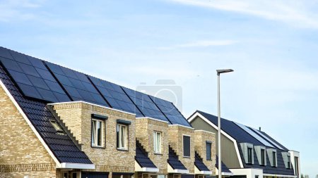 Téléchargez les photos : Zone de banlieue néerlandaise avec des maisons familiales modernes avec des panneaux solaires noirs sur le toit contre un sk ensoleillé,. Zonnepanelen, Zonne energie, Traduction : Panneau solaire, Énergie solaire - en image libre de droit