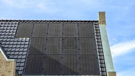Téléchargez les photos : Zone de banlieue néerlandaise avec des panneaux solaires noirs sur le toit contre un ciel ensoleillé Gros plan de la nouvelle maison avec des panneaux solaires noirs. Zonnepanelen, Zonne energie, Traduction : Panneau solaire, Énergie solaire - en image libre de droit