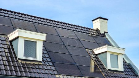 Foto de Zona suburbana holandesa con casas nuevas con paneles solares negros en el techo, primer plano de edificio nuevo con paneles solares negros. Zonnepanelen, Zonne energie, Traducción: Panel solar, Energía solar - Imagen libre de derechos