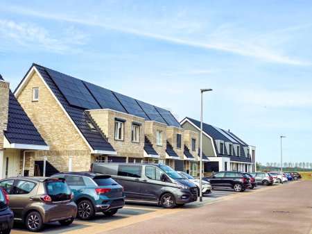 Téléchargez les photos : Maisons familiales néerlandaises avec panneaux solaires sur le toit contre un ciel ensoleillé. Zonnepanelen, Zonne energie, Traduction : Panneau solaire, énergie solaire, banlieue néerlandaise avec maisons familiales modernes, - en image libre de droit
