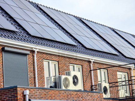 Foto de Unidad de bomba de calor de fuente de aire instalada al aire libre en una casa moderna con paneles solares en los Países Bajos, Zonnepanelen, Zonne energie, Traducción: Panel solar, Sun Energy - Imagen libre de derechos
