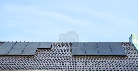 Foto de Casas de nueva construcción con paneles solares negros en el techo contra un cielo soleado Primer plano de una casa nueva con paneles solares negros. Zonnepanelen, Zonne energie, Traducción: Panel solar, Energía solar - Imagen libre de derechos